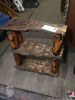 Front view of the three-tier solid wood live edge shelf with cylindrical supports and natural wood finish.