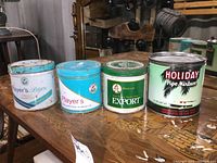 Four vintage metal tobacco tins arranged on wooden surface
