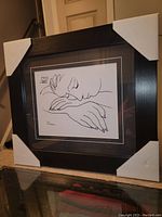Framed black and white line drawing print by Pablo Picasso, showing full frame with protective corner covers in place.