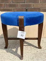 Front view of the Art Deco stool chair showing the vibrant blue fabric seat and wooden legs with decorative carved detail.