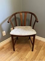 Front view of the mid century modern walnut stained wishbone chair showing curved bentwood backrest and upholstered seat.