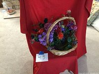 Basket with colorful artificial flowers loosely arranged, showing a variety of flower types and colors.