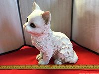 Side profile of white ceramic cat figurine showing textured fur and paint wear.
