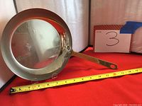 View of frying pan interior and handle with measuring tape showing size