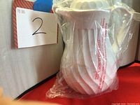 White thermos jug wrapped in plastic with a spiral grooved design and handle. Photo shows overall appearance and condition.