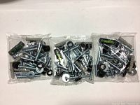Three sealed plastic bags each containing a mix of bolts, plastic wall anchors, washers, and mini spirit bubble levels.