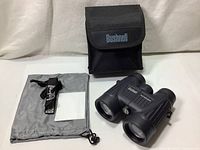 Wide view of binoculars with case, pouch, neck strap, and cleaning cloth.