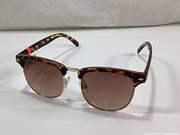 Front and side view of Joe Fresh tortoiseshell sunglasses with brown gradient lenses, showing frame details and branding.