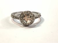 Front view showing round solid Swarovski crystal bezel set center with halo of smaller crystals and rhodium plated pave band.