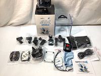 Full kit laid out with camera box, waterproof housing, multiple mounting accessories, remote, USB cable, cloth, adhesive pads.