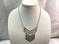 Full view of vintage silver tone chevron necklace displayed on white bust stand.