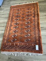Full view of smaller rectangular area rug laid flat on floor showing pattern and tassels.