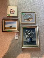 Four framed artworks arranged on carpet showing each piece's size and framing