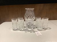 Six crystal highball glasses with hurricane lamp behind