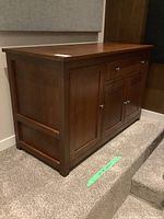 Side view of the custom made wood cabinet showing its medium-dark wood finish and recessed panel sides.