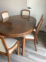 Full view of oval wooden dining table with four chairs, showing table surface and legs.