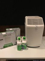 Photo showing Essick Air Products humidifier, two bottles of humidifier supplies, and Aircare evaporative filter box.