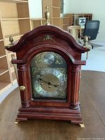 Front view of the wooden mantel clock showing brass clock face and decorative brass details