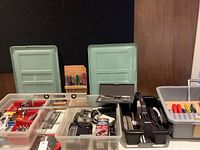 Assorted hand tools and small hardware items in plastic bins and trays including screwdrivers, clamps, level, and tape measure.