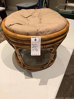 Rattan hassock full view showing round rattan frame and cushioned top