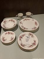 Photo showing sets of china pieces including teacups, saucers, side plates, bowls, and dinner plates arranged neatly, confirming quantity and design.