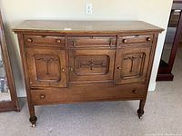 Front view of oak sideboard with three drawers and three carved doors