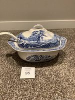Front view of the rectangular blue and white soup tureen with lid on a carpeted floor.