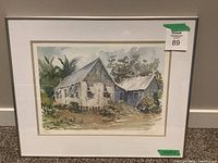 Full view of the framed watercolour painting depicting a rustic house with foliage, along with visible measurement tape indicating size.