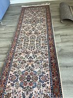 Full view of the wool hallway runner showing detailed floral and geometric border patterns, tassels at one end, and overall condition.