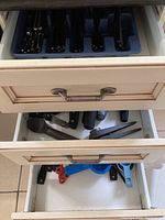 Three kitchen drawers showing cutlery trays and kitchen tools in drawers.