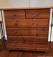 Front view of wood dresser showing five drawers and natural wood finish