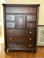 Front view showing eight drawers and one door with medium brown finish and wooden knobs.