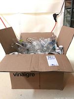 Box filled with over 20 clear glass drinking glasses in various sizes and styles.