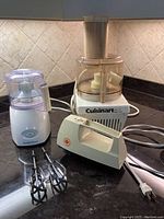 Photo showing Cuisinart food processor, Iona hand mixer with beaters, and Hamilton Beach food mill on countertop.
