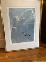 Full view of framed Robert Bateman print showing bird flying in front of large cloud formations.