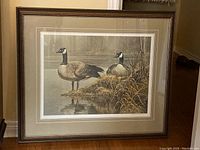 Frontal view of framed print showing two Canada geese by water