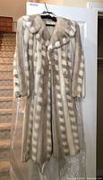 Full-length front view of striped mink fur coat hanging on a door
