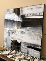 Front view of the large square mixed media abstract artwork showing the primary composition of black, white, and grey paint with gold thread accents.