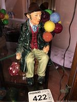 Front view of Royal Doulton The Balloon Man porcelain figurine showing seated man with colorful balloons and wearing period clothing