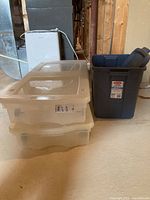 Three totes consisting of two translucent rolling totes stacked with lids and one grey Rubbermaid tote with lid.