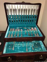 Three-tier chest open showing flatware arranged in turquoise velvet compartments