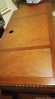 Top view of dark brown solid wood desk showing flat surface with cable hole and decorative carved edges.