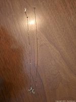 Photo showing full length of gold necklace with star pendant and letter S charm on wooden background.