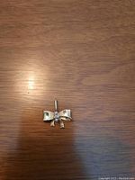 Front view of 14K gold bow pendant showing three center diamonds and polished bow shape.