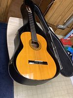 Jaguar acoustic guitar in open hard black case showing natural wood finish and black fretboard