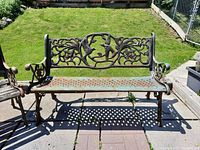 Full front view of cast iron bench on patio, showing lattice seat and decorative backrest