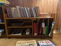 Front view of wooden bookshelf/record cabinet showing books and records inside compartments.
