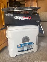 Photo showing the white hard-sided Igloo cooler with three black Coors Light soft cooler bags stacked on top in a garage setting.