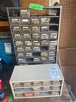 Large metal hardware drawer unit with many small labeled drawers.