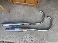 Two chrome exhaust pipes placed on a concrete floor.